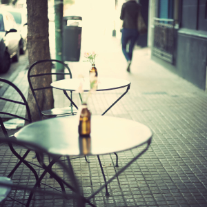 neighborhood scene with bistro tables on a sidewalk